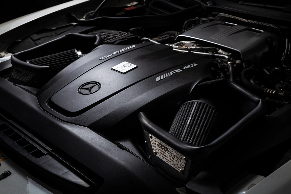 Close-up of a Mercedes-AMG engine bay featuring AMG-branded engine cover and high-performance air intake system.